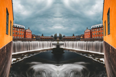 View of fountain in city against cloudy sky