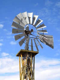 Low angle view of water pump windmill against sky on sunny day