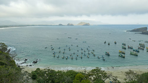 Aerial view of boats moored in sea against cloudy sky