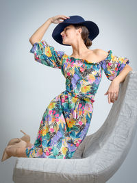 Young woman wearing hat on seat against wall