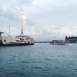 Boats in river against cloudy sky