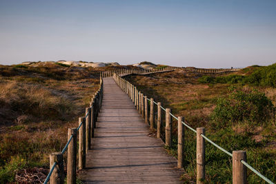 View of wooden footbridge against clear sky