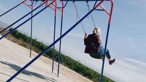 Boy playing on playground against sky