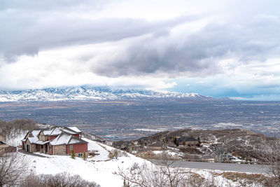 Scenic view of snow covered landscape and houses against sky