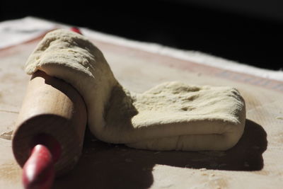 Close-up of dough and rolling pin in kitchen