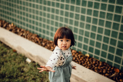 Portrait of smiling girl standing against brick wall