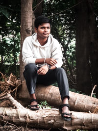 Portrait of young man sitting in forest