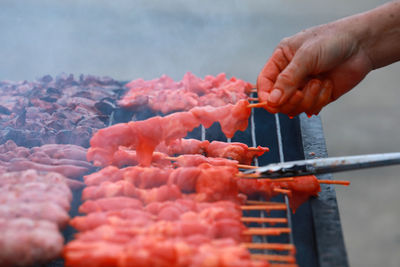 Person holding meat on barbecue grill