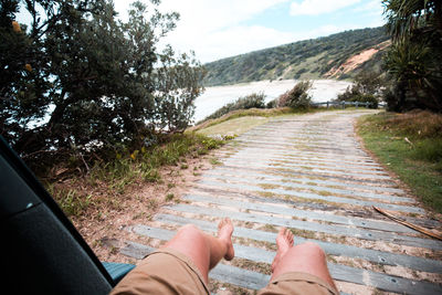 Low section of woman legs on water against sky
