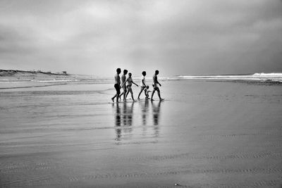 People walking at beach against sky