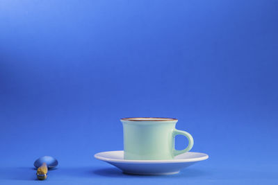 Close-up of coffee cup against blue background
