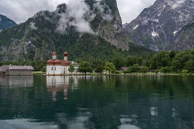 Scenic view of church by lake against mountains