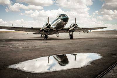 Military airplane on runway against cloudy sky