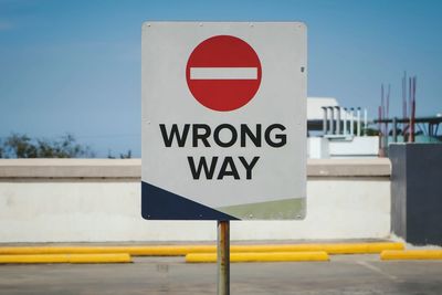 Close-up of road sign against sky