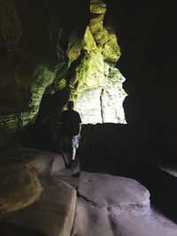 Rear view of woman standing in cave