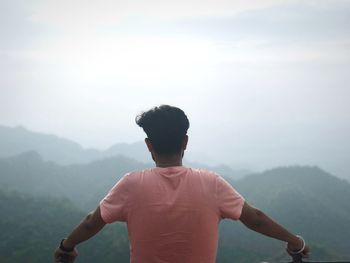 Rear view of man looking at mountain against sky