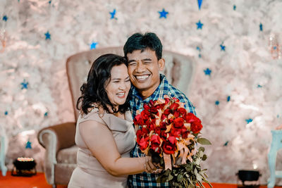 Happy couple with pink flower against blurred background