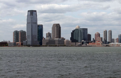 Sea by modern buildings against sky in city