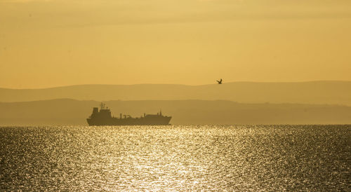 Silhouette boat on sea against sky during sunset