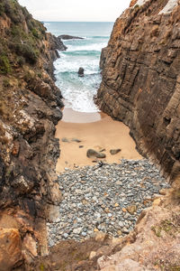 Rock formation on beach against sky