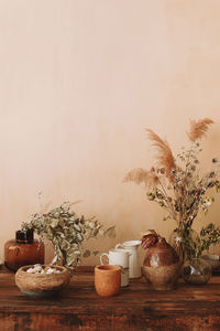 Lots of empty glassware and vases with dried flowers and plants on a wooden antique vintage table. 