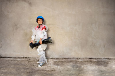 Portrait of young woman standing against wall