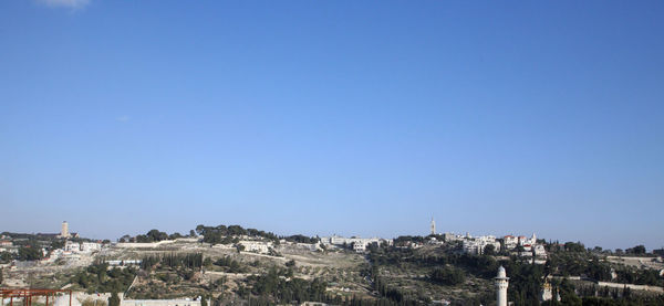 Buildings in city against clear blue sky