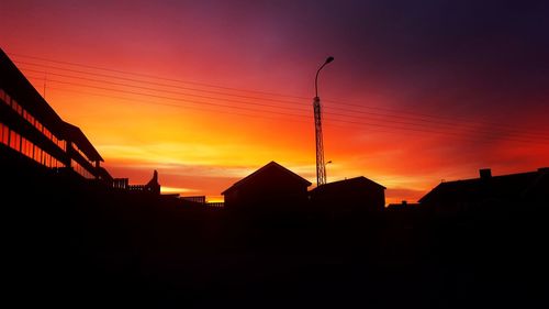 Silhouette buildings against orange sky