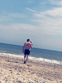 Full length rear view of shirtless man on beach