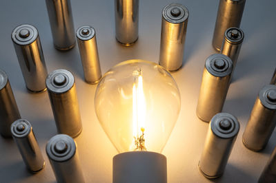 Light bulb turned on, with batteries next to it. accumulation and reuse of renewable energy.