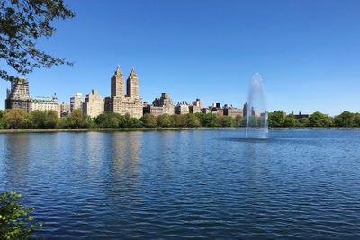 View of buildings by lake against sky