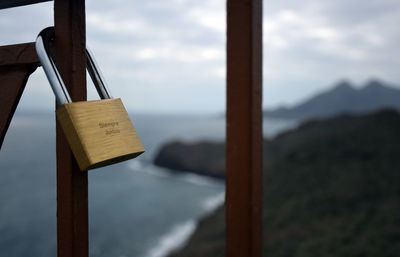 Close-up of padlocks hanging on wood against sky