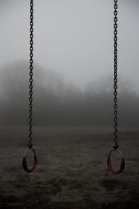 Close-up of swing in playground against sky