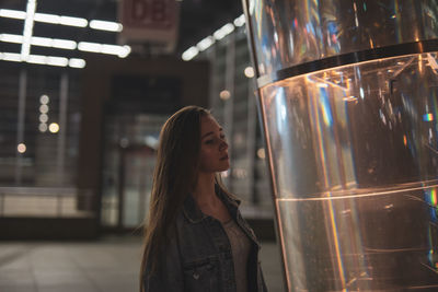 Woman by metal with reflection at night