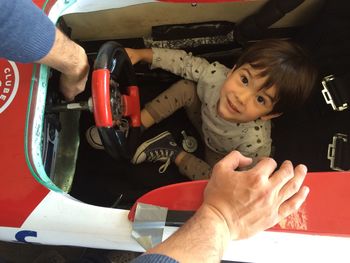 Cropped hands of father by son sitting in bumper car