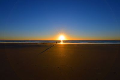 Scenic view of beach against clear sky at sunset