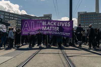 People walking on street in city against sky