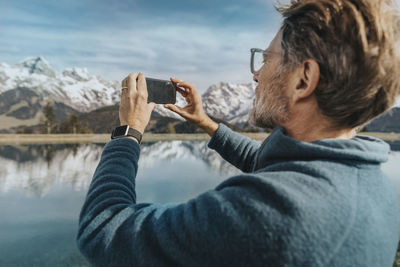 Rear view of man photographing on mobile phone