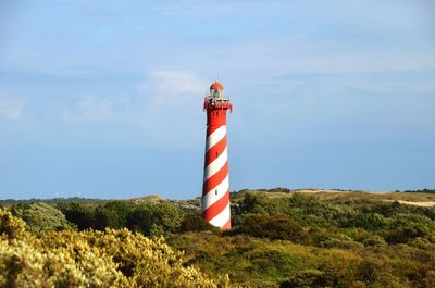 Lighthouse on field against sky