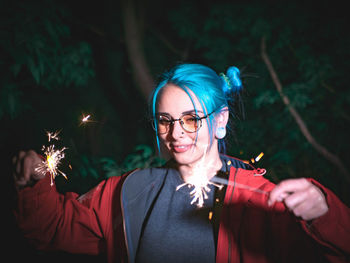 Close-up of young woman burning sparklers at night