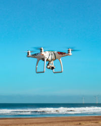 Helicopter flying over sea against clear blue sky