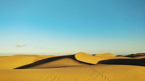 Close-up of sand dunes against clear blue sky