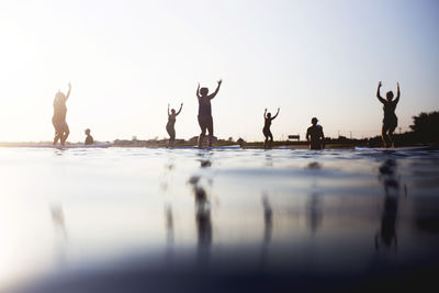 Reflection of people in water against sky