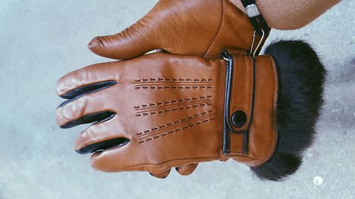 Cropped hand holding leather gloves during winter