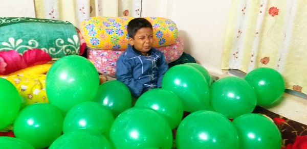 Full length portrait of smiling boy with multi colored balloons