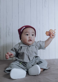 Cute baby boy looking away while sitting on floor