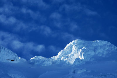 Scenic view of snowcapped mountains against blue sky