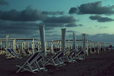 Deck chairs on beach against sky