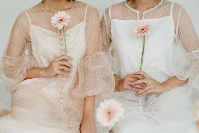 2 midsection of woman with flowers on white background