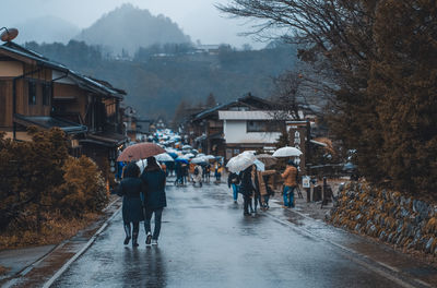 People walking on wet street in city during rainy season